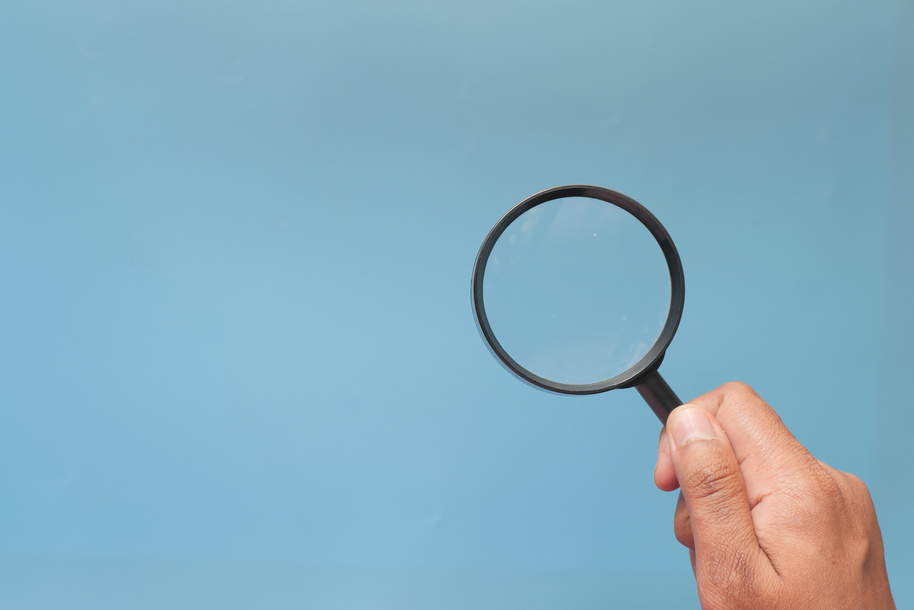 Hand Holding Magnifying Glass on Color Background